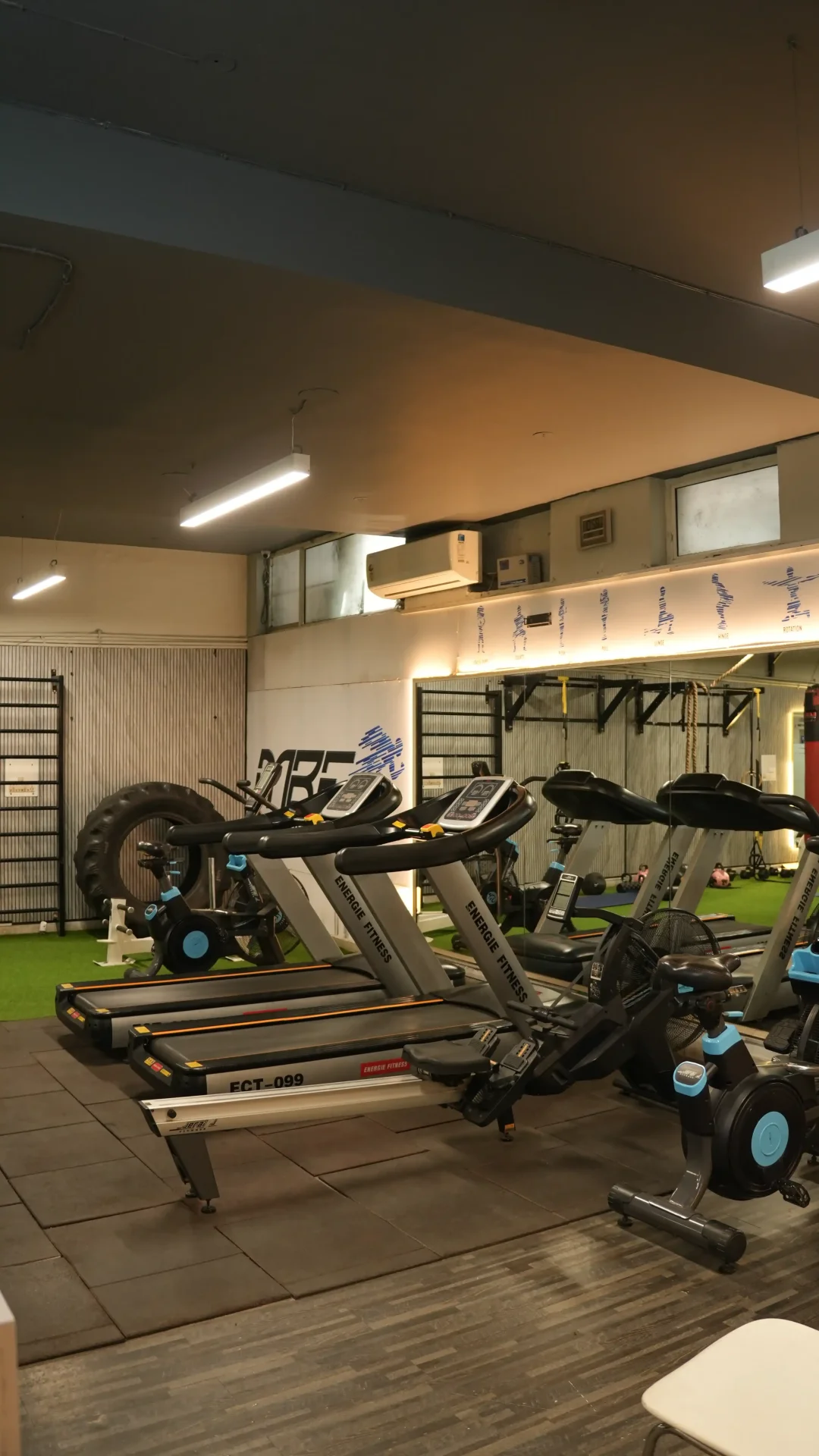 Wide cardio floor with treadmills, bikes, turf area, and functional rig